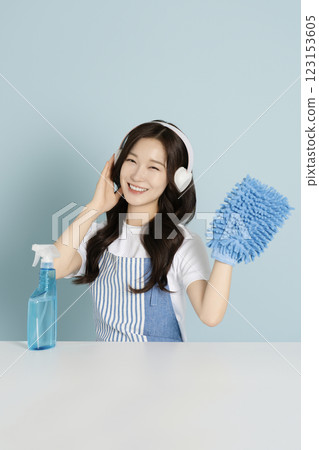 A woman in her 20s wearing a headset and holding detergent and a mop for cleaning 123153605