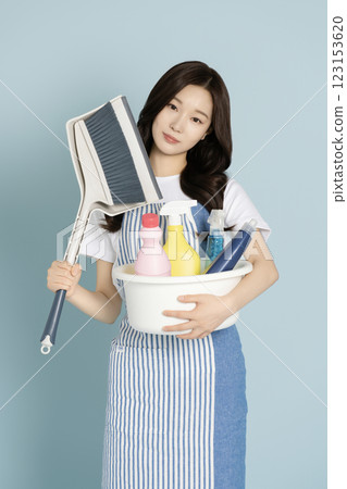 A woman in her 20s holding a basin containing cleaning tools for cleaning 123153620