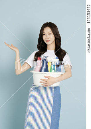 A woman in her 20s holding a basin containing cleaning tools for cleaning 123153632