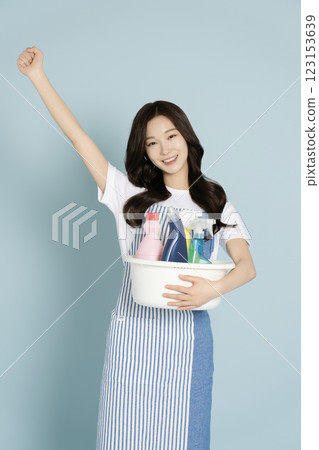 A woman in her 20s holding a basin containing cleaning tools for cleaning 123153639