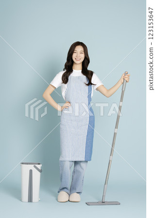 A woman in her 20s mopping the floor with a gunny mop A woman in her 20s mopping the floor with a gunny mop 123153647