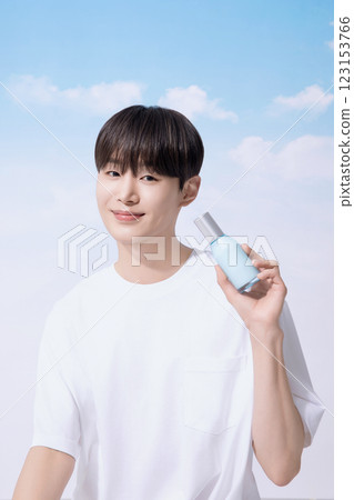 Young man holding basic cosmetics products and standing with clouds in the background 123153766