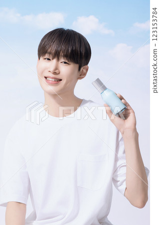 Young man holding basic cosmetics products and standing with clouds in the background Young man holding basic cosmetics products and standing with clouds in the background 123153784