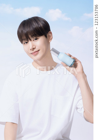 Young man holding basic cosmetics products and standing with clouds in the background Young man holding basic cosmetics products and standing with clouds in the background 123153786