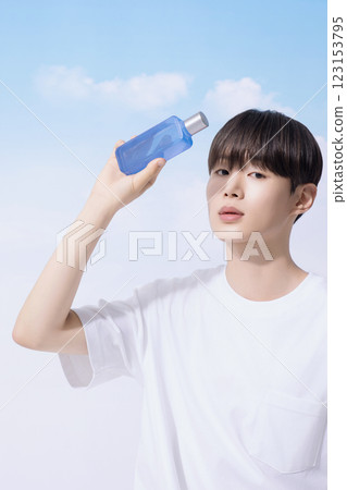 Young man holding basic cosmetics products and standing with clouds in the background 123153795