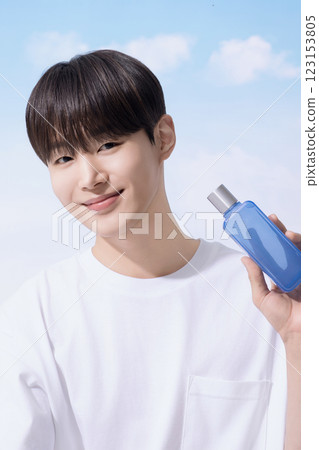 Young man holding basic cosmetics products and standing with clouds in the background 123153805