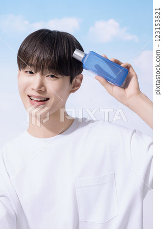 Young man holding basic cosmetics products and standing with clouds in the background 123153821