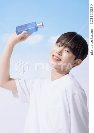 Young man holding basic cosmetics products and standing with clouds in the background Young man holding basic cosmetics products and standing with clouds in the background 123153829