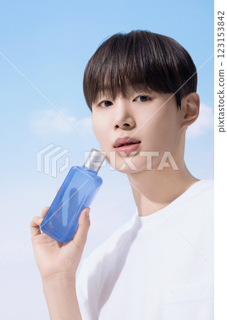 Young man holding basic cosmetics products and standing with clouds in the background 123153842