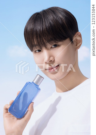 Young man holding basic cosmetics products and standing with clouds in the background 123153844
