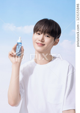 Young man holding basic cosmetics products and standing with clouds in the background 123153846