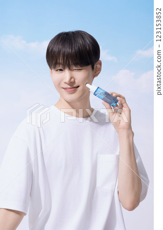 Young man holding basic cosmetics products and standing with clouds in the background Young man holding basic cosmetics products and standing with clouds in the background 123153852