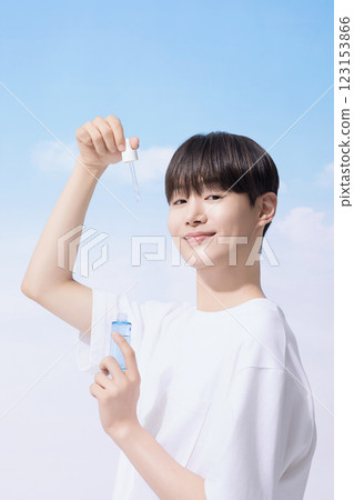 Young man holding basic cosmetics products and standing with clouds in the background 123153866