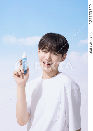 Young man holding basic cosmetics products and standing with clouds in the background 123153869