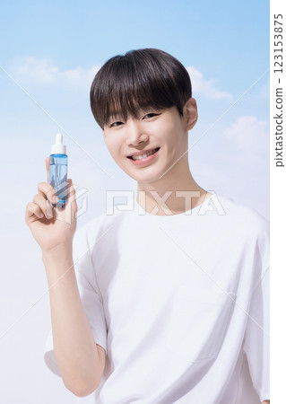 Young man holding basic cosmetics products and standing with clouds in the background 123153875