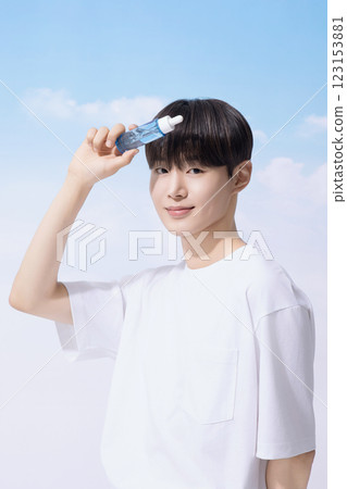 Young man holding basic cosmetics products and standing with clouds in the background Young man holding basic cosmetics products and standing with clouds in the background 123153881