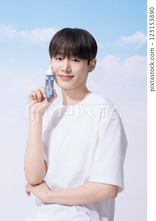 Young man holding basic cosmetics products and standing with clouds in the background 123153890