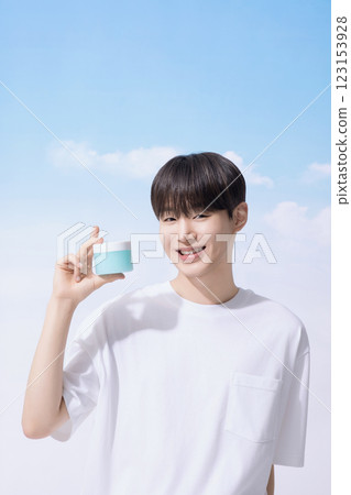 Young man holding basic cosmetics products and standing with clouds in the background Young man holding basic cosmetics products and standing with clouds in the background 123153928