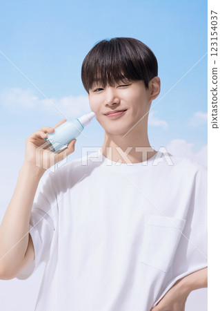 Young man holding basic cosmetics products and standing with clouds in the background Young man holding basic cosmetics products and standing with clouds in the background 123154037