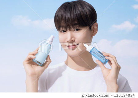 Young man holding basic cosmetics products and standing with clouds in the background Young man holding basic cosmetics products and standing with clouds in the background 123154054