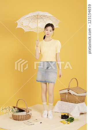 A woman in her 20s spreading out a mat and enjoying a picnic 123154659