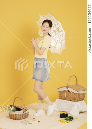 A woman in her 20s spreading out a mat and enjoying a picnic 123154663