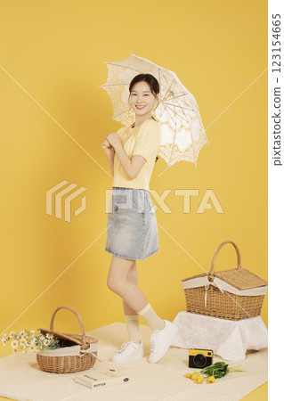A woman in her 20s spreading out a mat and enjoying a picnic 123154665