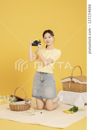 A woman in her 20s spreading out a mat and enjoying a picnic 123154666
