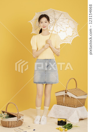 A woman in her 20s spreading out a mat and enjoying a picnic 123154668