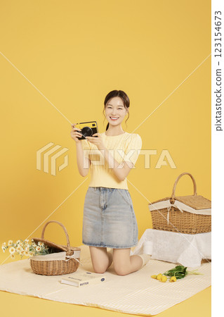 A woman in her 20s spreading out a mat and enjoying a picnic 123154673