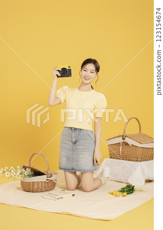 A woman in her 20s spreading out a mat and enjoying a picnic 123154674
