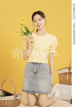 A woman in her 20s spreading out a mat and enjoying a picnic 123154678