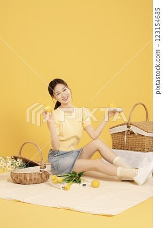 A woman in her 20s spreading out a mat and enjoying a picnic 123154685