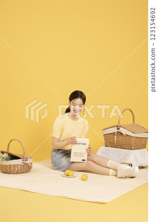 A woman in her 20s spreading out a mat and enjoying a picnic A woman in her 20s spreading out a mat and enjoying a picnic 123154692