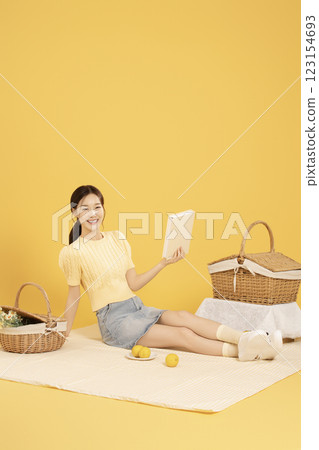 A woman in her 20s spreading out a mat and enjoying a picnic A woman in her 20s spreading out a mat and enjoying a picnic 123154693