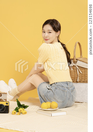 A woman in her 20s spreading out a mat and enjoying a picnic 123154698