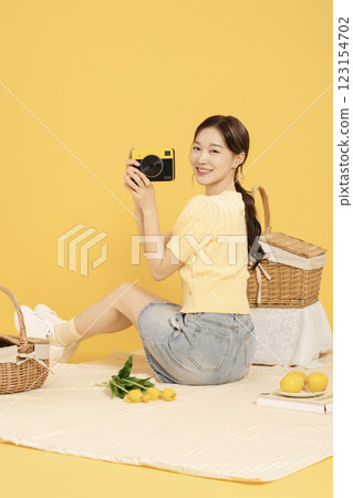 A woman in her 20s spreading out a mat and enjoying a picnic 123154702