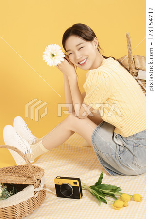 A woman in her 20s spreading out a mat and enjoying a picnic 123154712