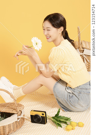 A woman in her 20s spreading out a mat and enjoying a picnic 123154714