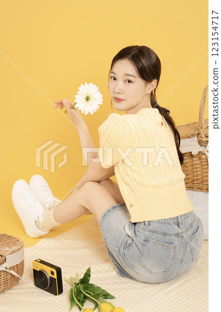 A woman in her 20s spreading out a mat and enjoying a picnic 123154717