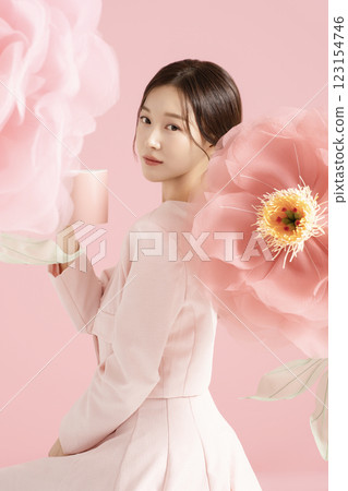 An innocent woman in her 20s wearing a pink two-piece with a large flower in the background. 123154746