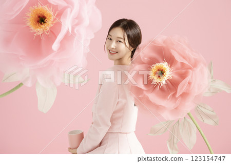 An innocent woman in her 20s wearing a pink two-piece with a large flower in the background. 123154747