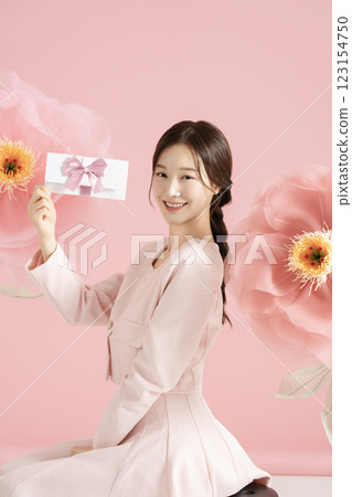 An innocent woman in her 20s wearing a pink two-piece with a large flower in the background. 123154750