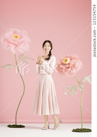 An innocent woman in her 20s wearing a pink two-piece with a large flower in the background. 123154754