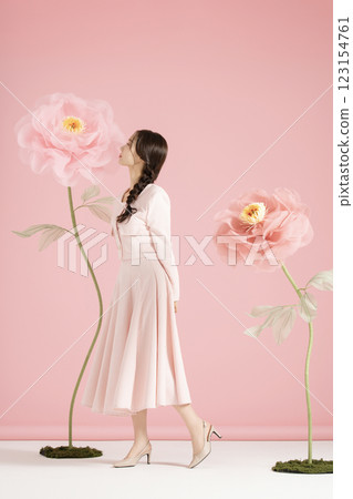 An innocent woman in her 20s wearing a pink two-piece with a large flower in the background. 123154761
