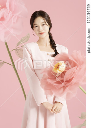 An innocent woman in her 20s wearing a pink two-piece with a large flower in the background. 123154769