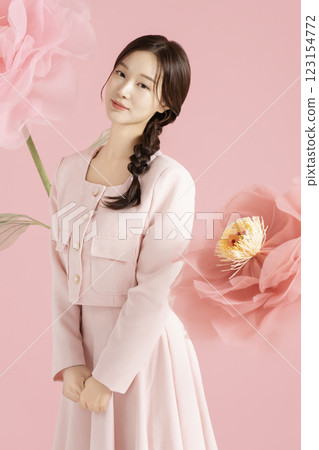 An innocent woman in her 20s wearing a pink two-piece with a large flower in the background. 123154772