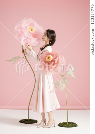 An innocent woman in her 20s wearing a pink two-piece with a large flower in the background. An innocent woman in her 20s wearing a pink two-piece with a large flower in the background. 123154779