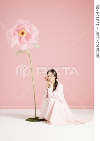 An innocent woman in her 20s wearing a pink two-piece with a large flower in the background. An innocent woman in her 20s wearing a pink two-piece with a large flower in the background. 123154788