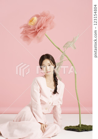 An innocent woman in her 20s wearing a pink two-piece with a large flower in the background. An innocent woman in her 20s wearing a pink two-piece with a large flower in the background. 123154804